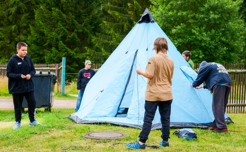 Kids bauen gemeinsam ein Zelt auf.